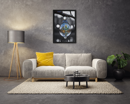Framed canvas art print of a colorful city skyline reflected in a water droplet. Features unique abstract photography with vibrant colors against a monochrome background. Modern and stylish wall decor.